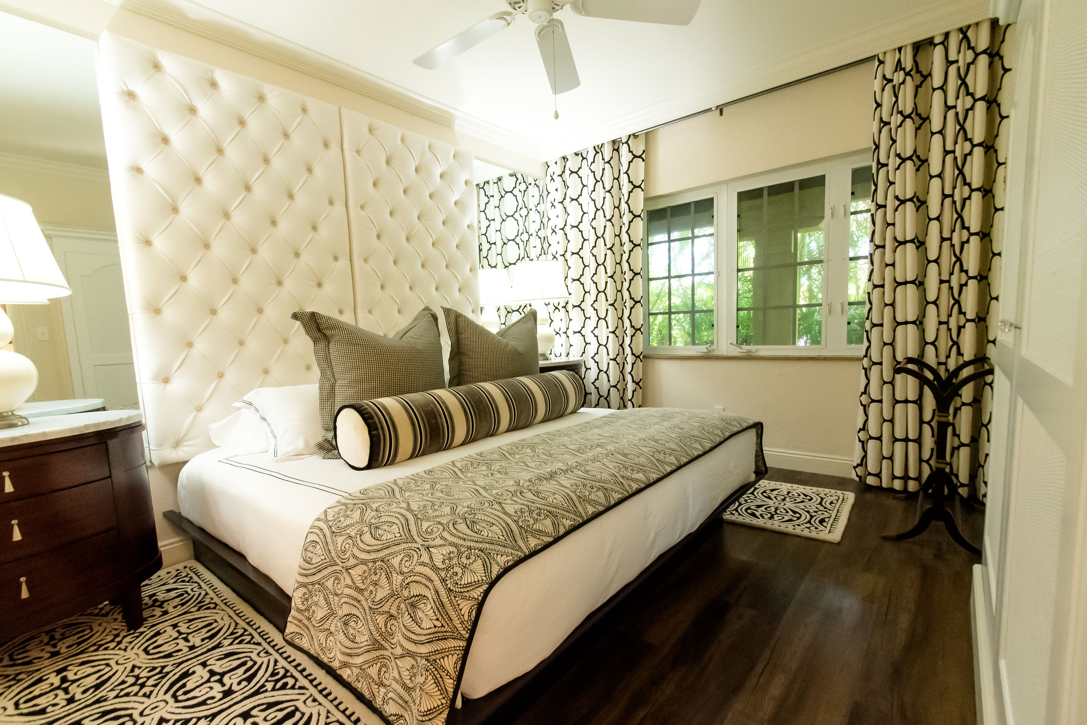 A wide view of a hotel room with a bed, nightstand, and window.